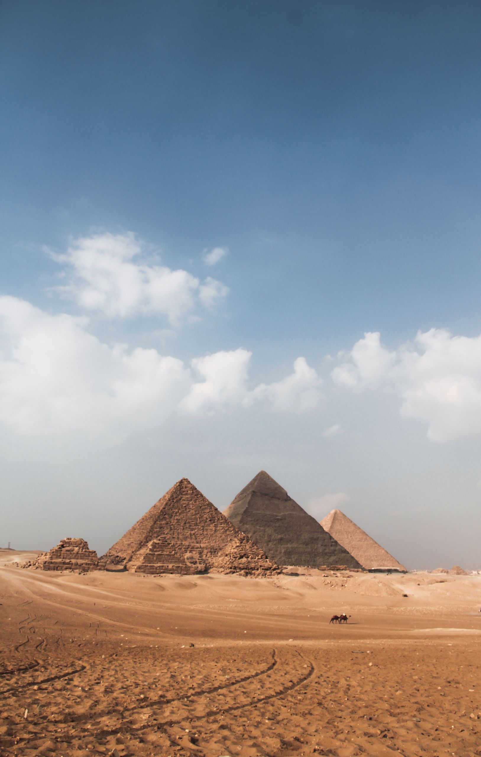 Explore the stunning Giza Pyramids under a vibrant blue sky, showcasing ancient architecture and desert scenery.
