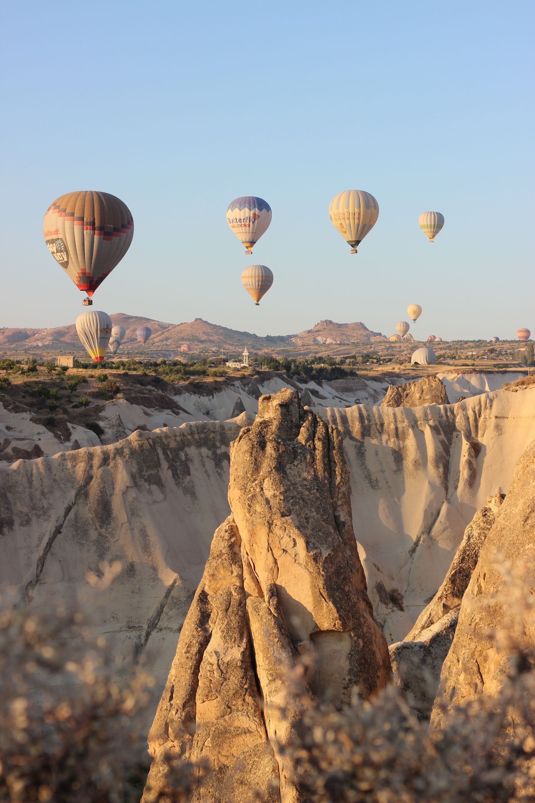 Hot air balloons soar over Cappadocia's iconic rock formations at sunrise, showcasing a breathtaking aerial view.
